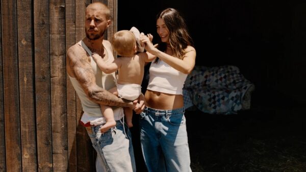 Justin Bieber carrying his son and his wife hailey bieber standing next to him rubbing their son's head
